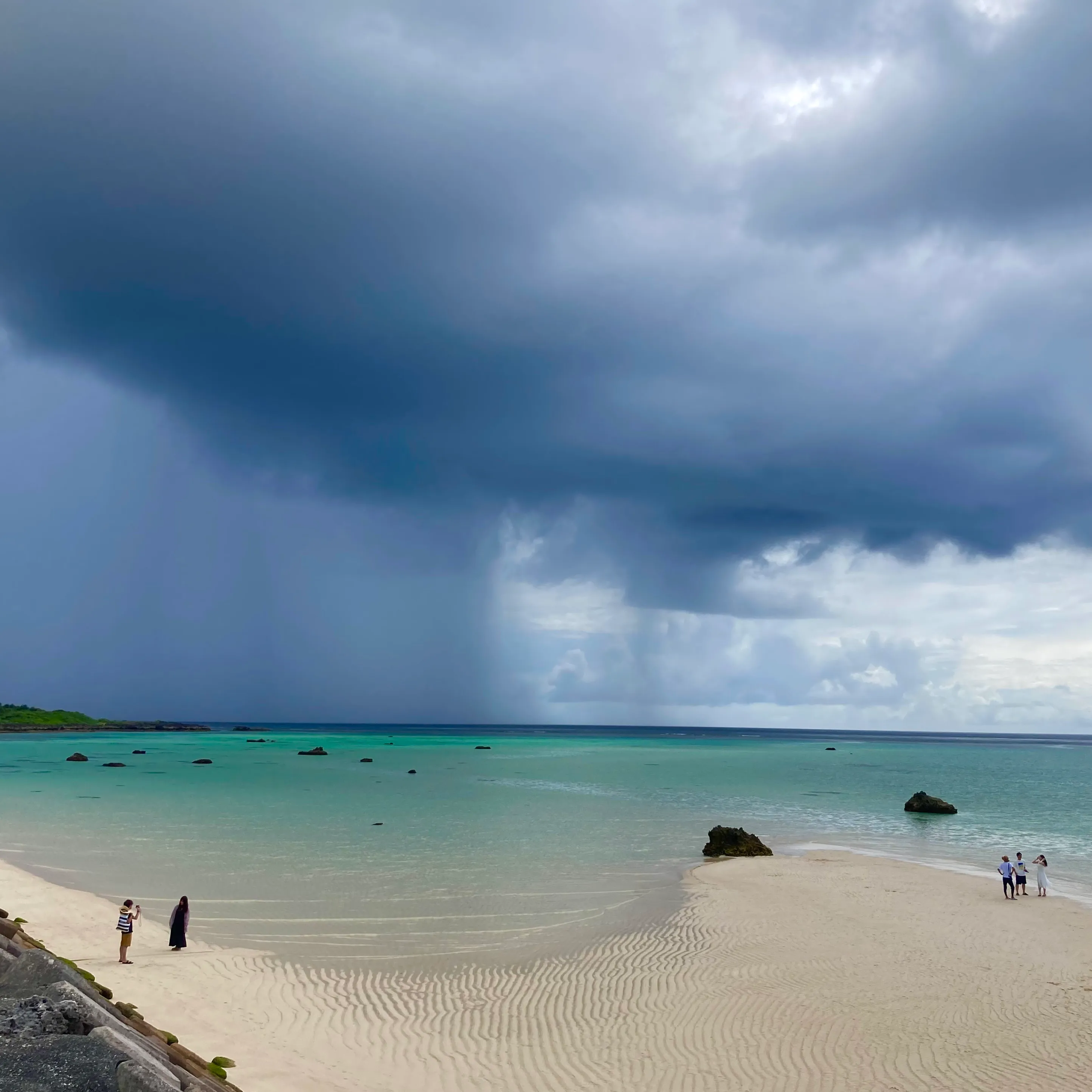 Dark storm clouds gathering over a turquoise beach on Miyakojima